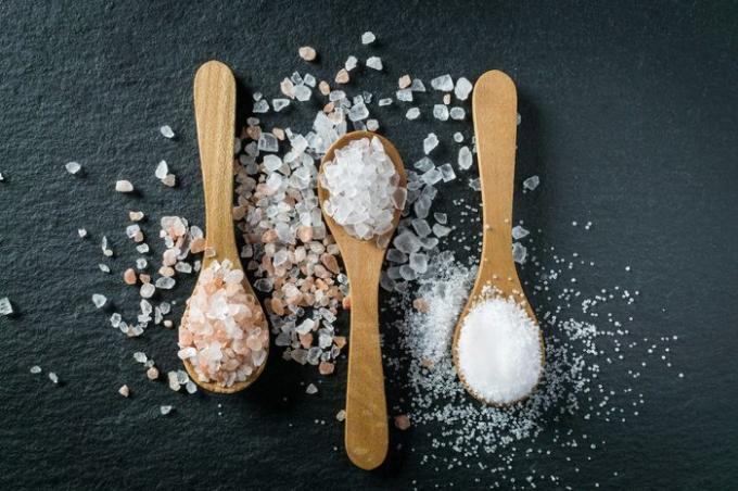 Diferentes tipos de sal. Sal de mar, del Himalaya y de cocina. Vista superior de tres cucharas de madera sobre fondo negro