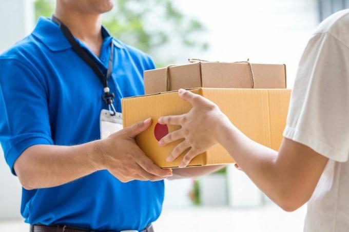 Kvinnehånd som godtar levering av esker fra leveringsmann