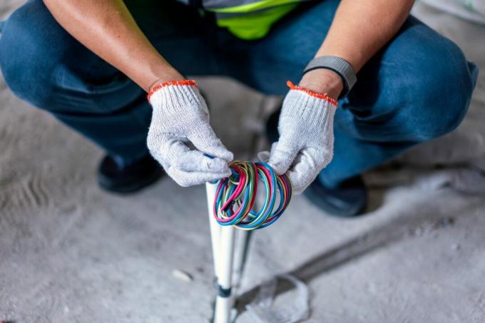 Närbild av byggnadsarbetare som reparerar elektrisk tråd på byggarbetsplatsen