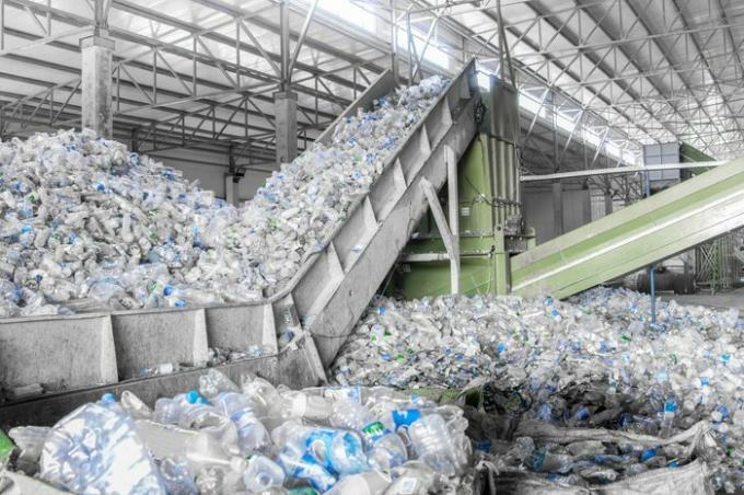 покретне степенице у крупном плану са гомилом пластичних боца у фабрици за прераду и рециклажу. Постројење за рециклажу ПЕТ -а