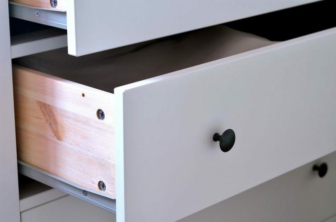 Atviro balto laminuoto stalčiaus su žalvarine rankena detalė