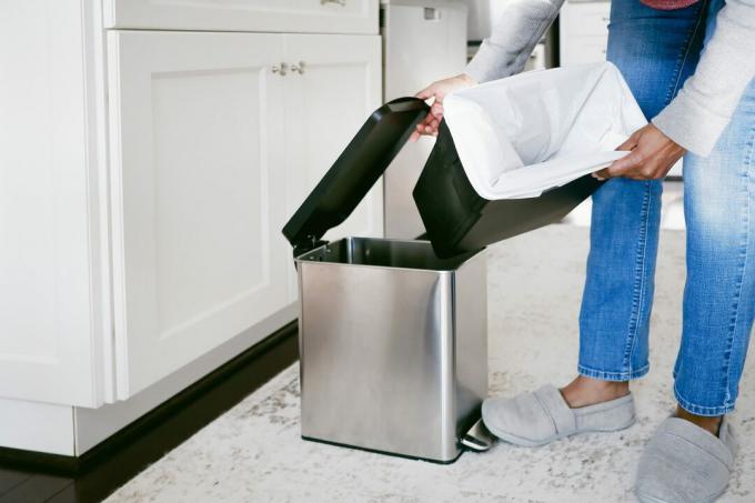 La donna sostituisce il sacco della spazzatura della cucina