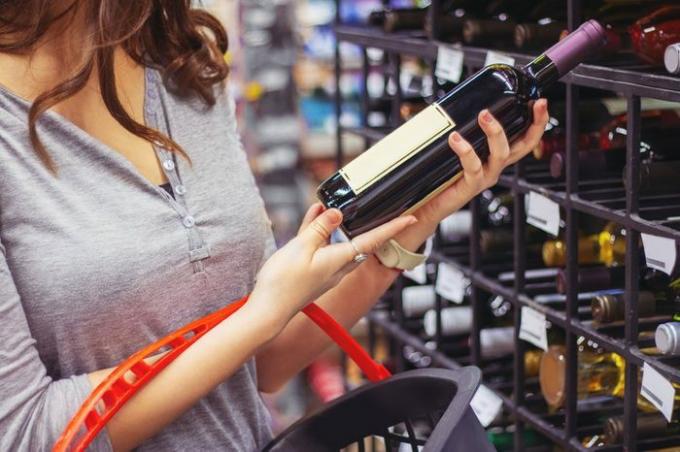 Mujer comprando y sosteniendo una botella de vino