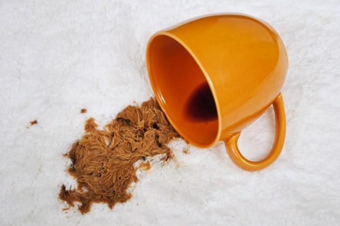 Kopp kaffe som spillts ut på mattan/ spillt kaffe på vitt