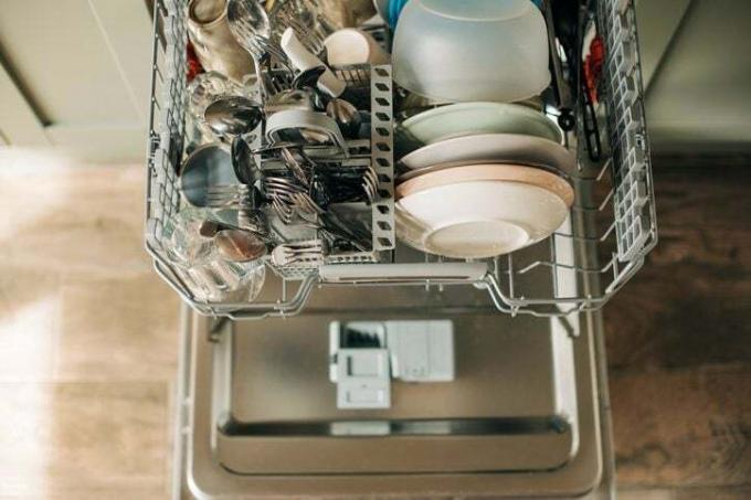 Åpen oppvaskmaskin med rent servise på det hvite kjøkkenet