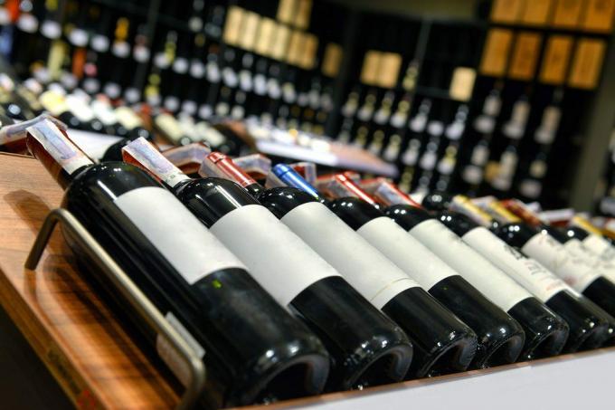 Raudonasis ir baltasis vynas buteliuose vyno parduotuvėje