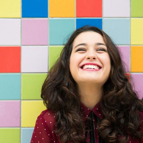 Ragazza felice che ride su uno sfondo di piastrelle colorate. Concetto di gioia; ID Shutterstock 332500766
