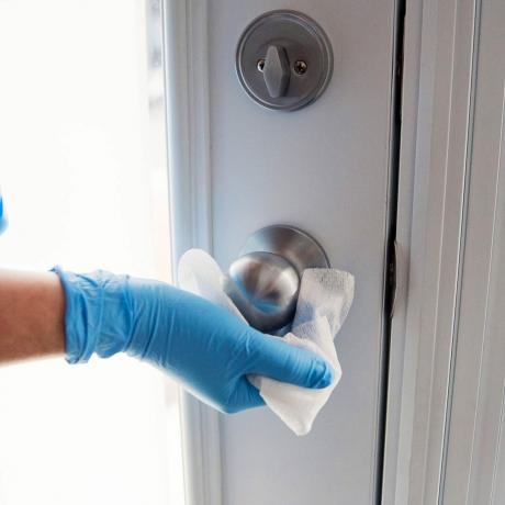 Tangan dengan sarung tangan menyeka gagang pintu tisu antibakteri