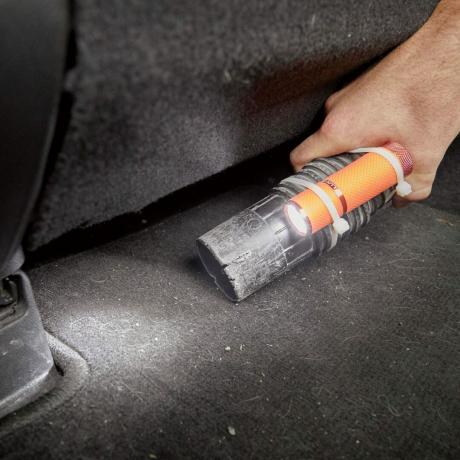 linterna al final de una manguera de vacío de taller que limpia el interior de un automóvil