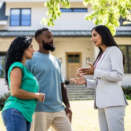 Reunión de pareja con agente de bienes raíces en frente de casa
