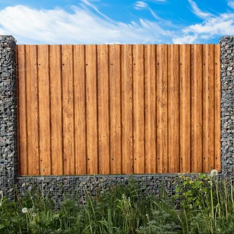 गेबियन बाड़। लकड़ी के तख्तों के खंडों के साथ पत्थरों से भरी पोस्ट। देहात शैली। बाहरी उद्यान तत्व डिजाइन। सुरक्षा दीवार। प्राकृतिक सामग्री। पृथक। प्रकृति बनावट। क्लोज़ अप