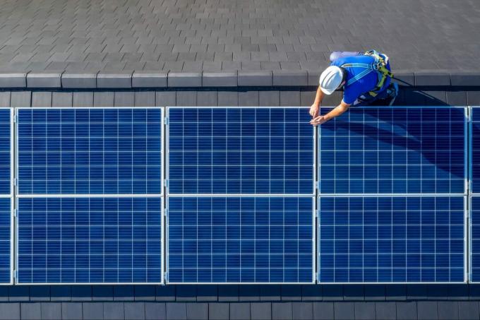 Installateur de panneaux solaires installant des panneaux solaires sur le toit d'une maison moderne