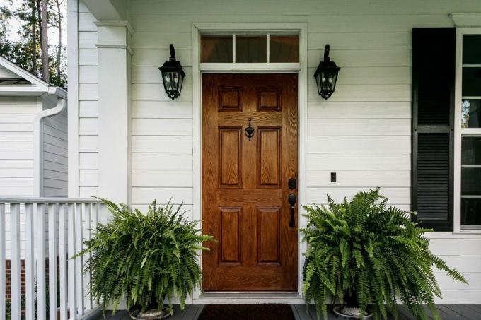 Porta da frente de madeira marrom de uma casa do sul com revestimento branco
