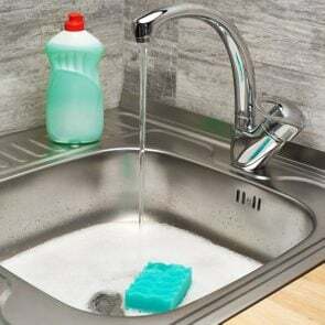 Akan musluk suyu, yeşil temizleme süngeri ve bir şişe sıvı deterjanla köpükle dolu mutfak lavabosunu kapatın; Shutterstock Kimliği 640551559; İş (TFH, TOH, RD, BNB, CWM, CM): TOH