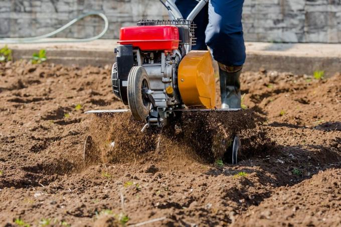 Πανό. Ο Άνθρωπος Αγρότης οργώνει τη γη με έναν καλλιεργητή. Γεωργικά μηχανήματα: καλλιεργητής για άροση στον κήπο, μηχανοκίνητος καλλιεργητής.