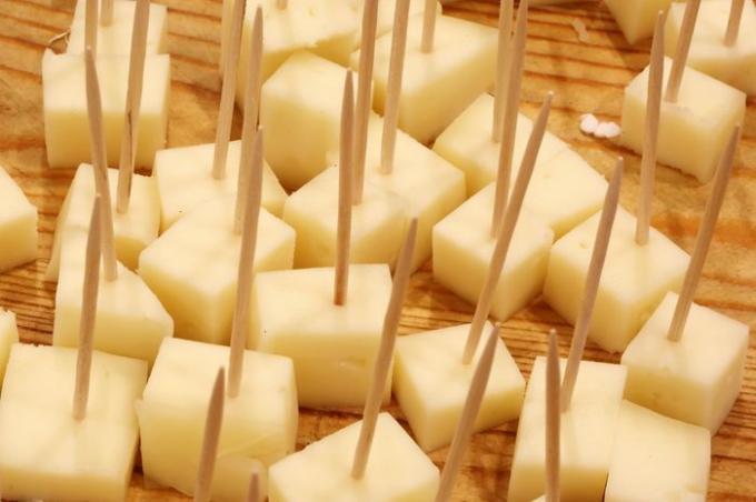 Degustaciones de queso fresco con palillos de dientes en la tienda de quesos sobre la tabla de cortar