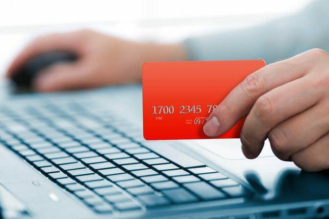 Mann som holder kredittkort i hånden og skriver inn sikkerhetskode ved hjelp av tastaturet til det bærbare datamaskinen
