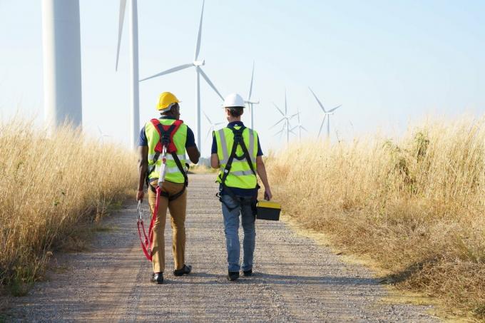 Zadní pohled na pracovníky větrné turbíny diskutující o práci na energii větrné farmy