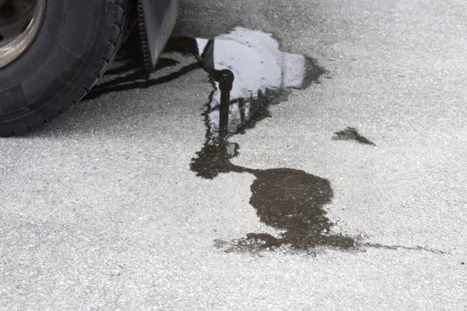 Mancha de aceite en el pavimento debajo del coche. Asfalto sucio debajo del coche.