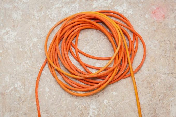 оранжев удължителен кабел върху под от шперплат