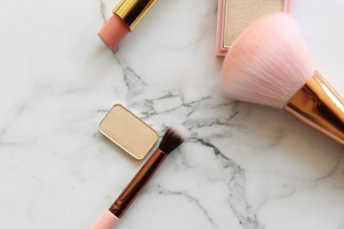 Guld og lyserøde makeupobjekter mod kopi af hvid marmor.