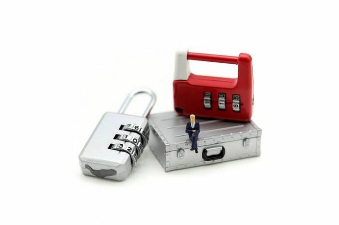 Minyatür insanlar: metal güvenlik kilidi anahtarının üzerinde oturan işadamı.