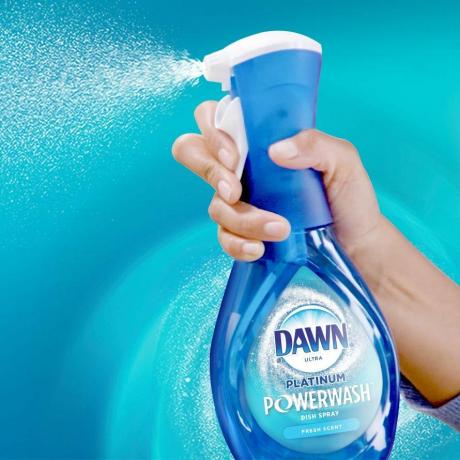 Mão pulverizando Dawn Power Wash com um fundo azul-petróleo