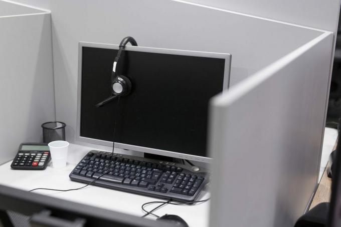 Tietokone ja kuulokkeet tyhjässä puhelinkeskuksen toimistossa