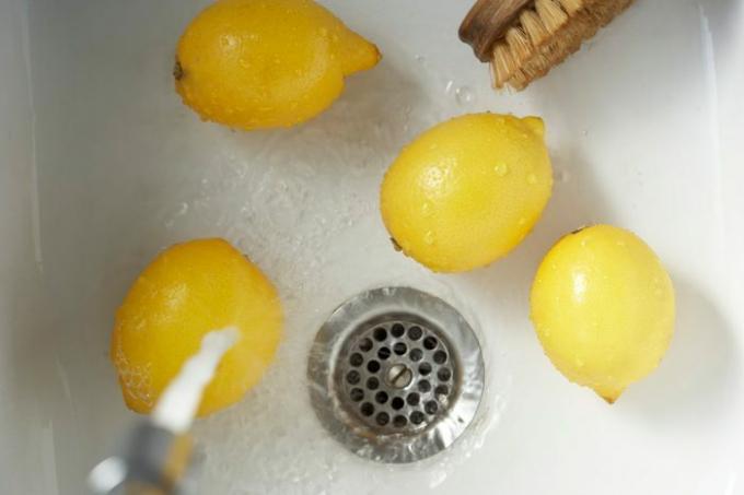 Очистка лимонов овощной щеткой в ​​раковине, вид сверху