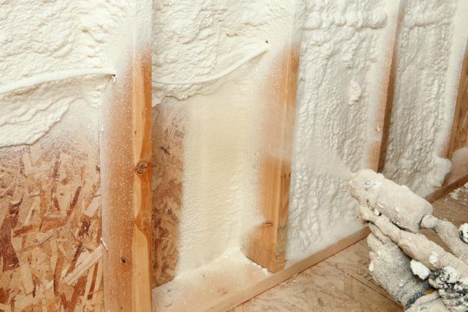 Operaio edile che spruzza isolamento in schiuma espandibile tra i montanti a parete