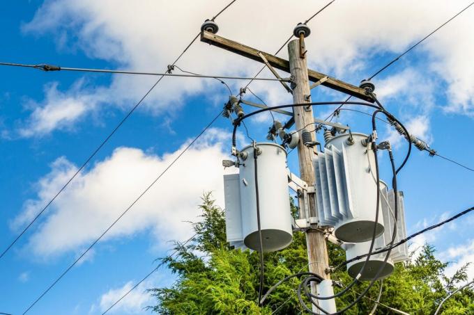 Elektrisitetsstolpe med transformatorer og blå himmel