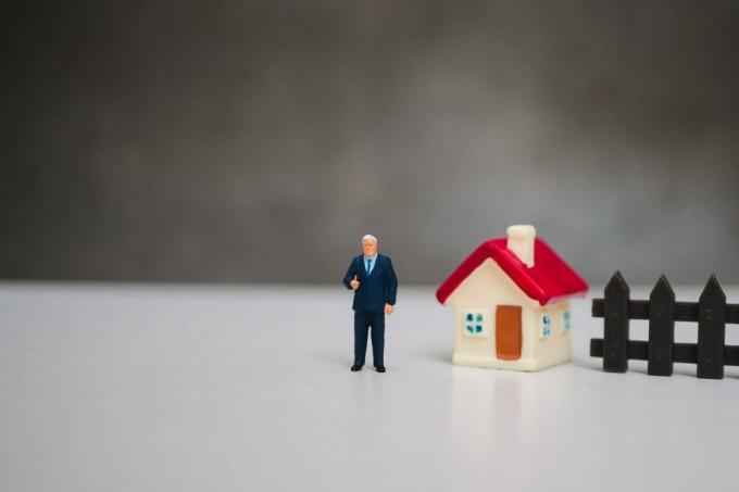 Pessoas em miniatura, empresário em pé com uma mini casa usando como conceito de negócio e família