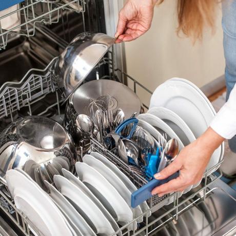Mujer adulta descarga lavavajillas en la cocina
