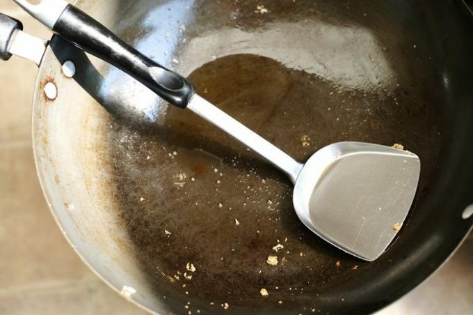 Прљава тава са стругаром и уљем у гвозденој посуди након што сте завршили са кувањем хране на Тајланду