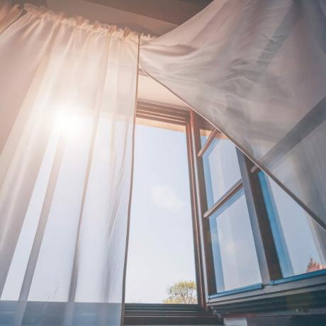 Sol de la mañana brillante en la ventana abierta a través de las cortinas