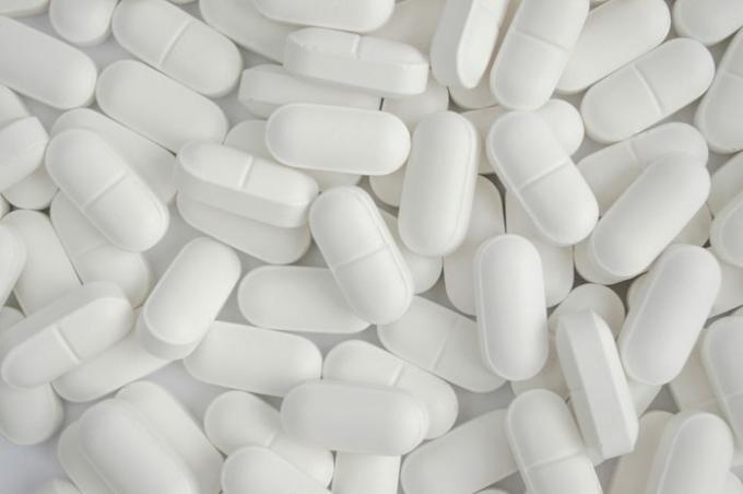 Pilha de pílulas brancas sobre fundo, saúde e medicina.