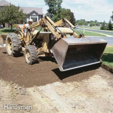 L'excavatrice roule sur la terre pour construire une allée d'asphalte