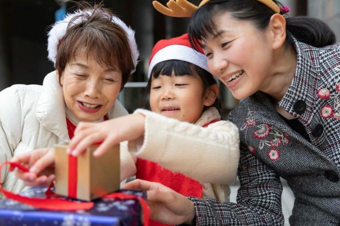 Família de várias gerações aproveitando o Natal embrulhando presentes e usando acessórios divertidos e festivos