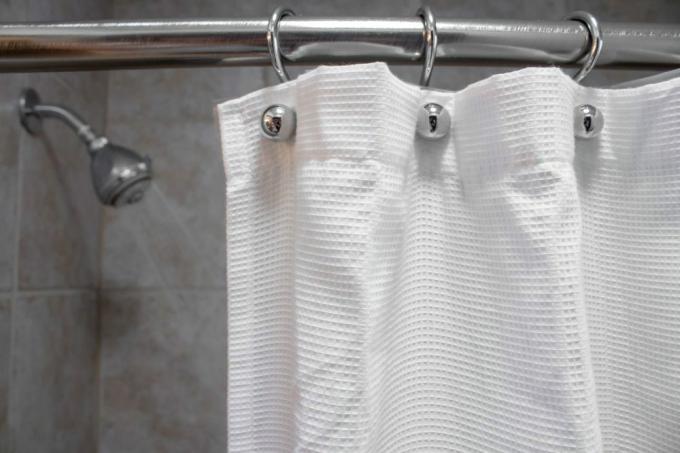 een wit douchegordijn in een lege douche met water UIT close-up shot