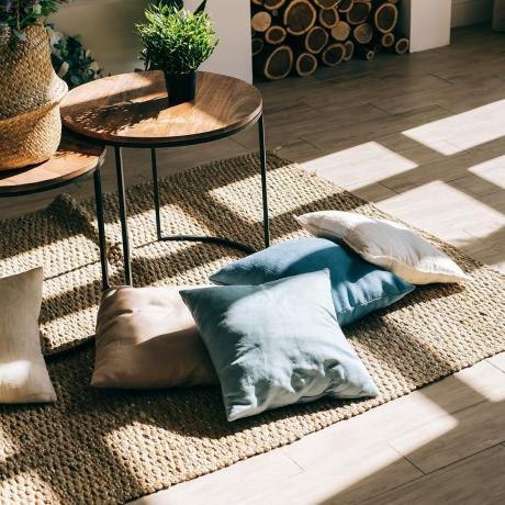 Interno del luminoso soggiorno in stile scandinavo con tavolino e cuscini sul pavimento
