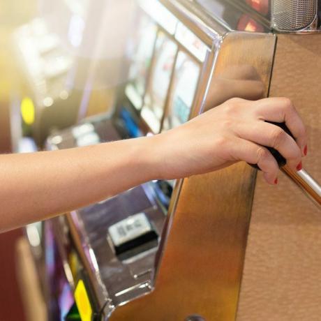 Femeie care trage de mânerul unui slot machine dintr-un cazinou. Jocuri de noroc, noroc, risc și concept de jackpot câștigător. Jucător jucând în Las Vegas sau Atlantic City.