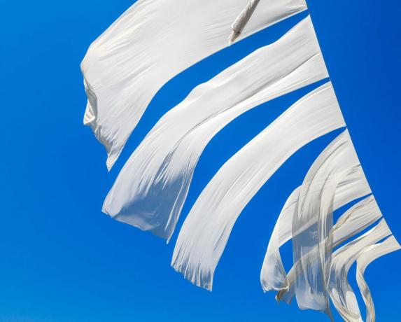 Πλυντήριο ρούχων, λευκά σεντόνια που κρέμονται στα άπλωμα σε μια φωτεινή μπλε μέρα