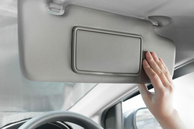 hånd som holder solskjerminteriør inne i bilen