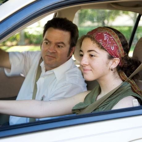 Тинејџерка проверава огледало на страни возача док отац гледа у аутомобилу