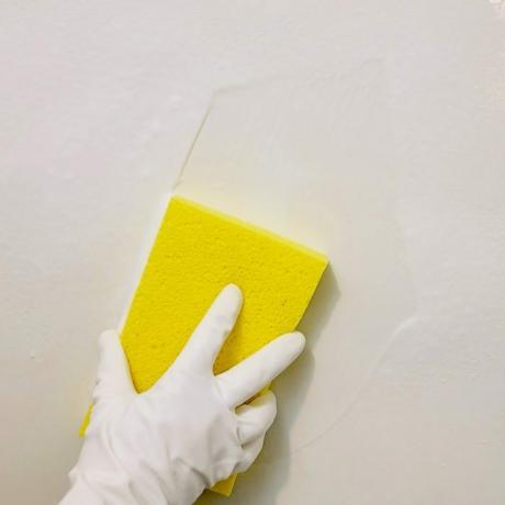 शॉवर की दीवारों को पीले स्पंज से साफ करना