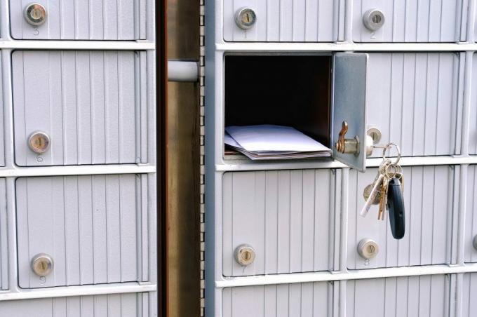 Porta della cassetta postale suburbana aperta con chiavi penzolanti e posta visibile nell'apertura
