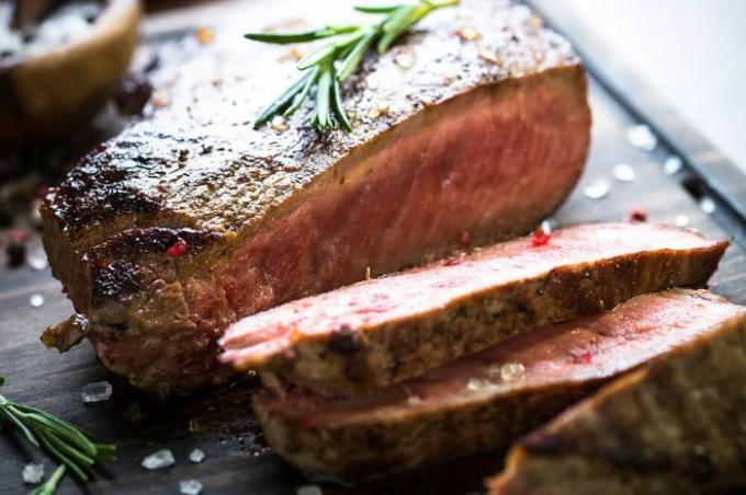 Daging panggang segar. Steak daging sapi panggang sedang langka di talenan. Merapatkan.