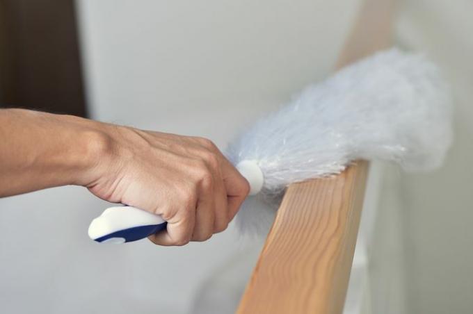 close de um jovem limpando a casa com um espanador de microfibra branco