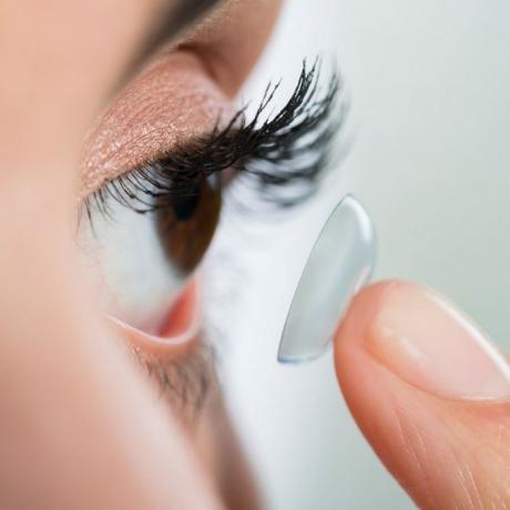 Krupni plan mlade žene koja nosi kontaktne leće kod kuće