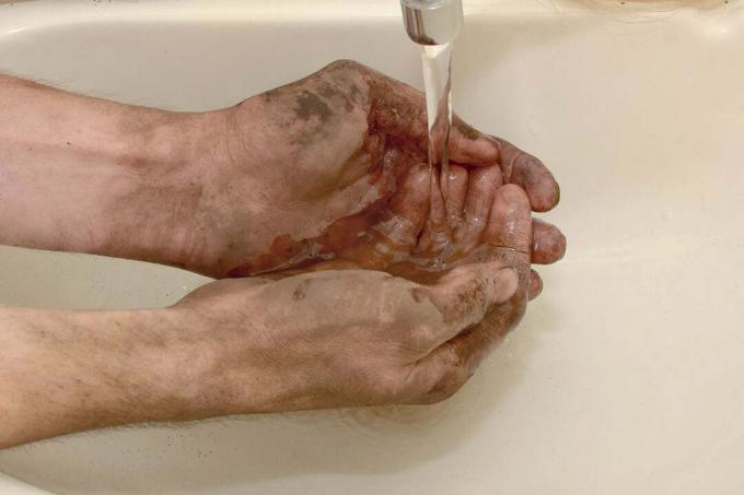 Мужчина моет грязные руки после работы на улице